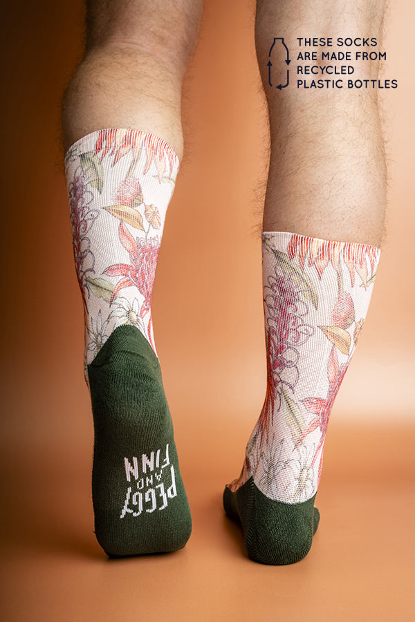 Sustainable socks featuring a detailed pattern of vibrant native flowers in shades of pink, red, and green, crafted from recycled materials