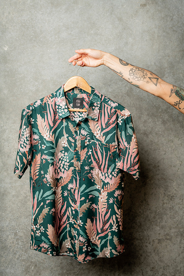 Hanging casual teal shirt adorned with artistic floral designs for a fresh summer look