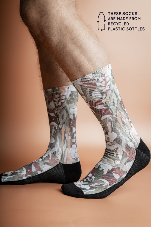 Eco-friendly socks with a Spotted Gum tree print, featuring a mix of earth tones like terracotta and sage on a rust-colored background